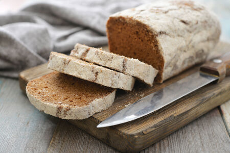 Sliced rye bread on cutting board closeup on wooden backgroundの写真素材