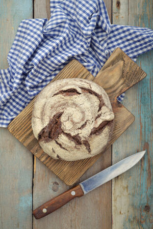 Rye round bread  on cutting board with knife on wooden backgroundの写真素材