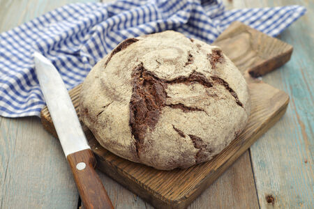 Rye round bread  on cutting board with knife on wooden background
の写真素材