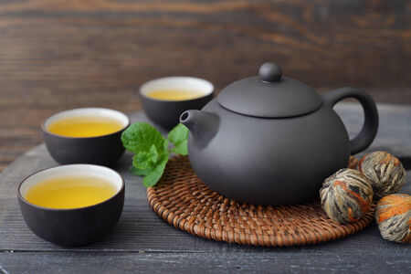 Green tea in cups with mint and teapot on wooden backgroundの写真素材