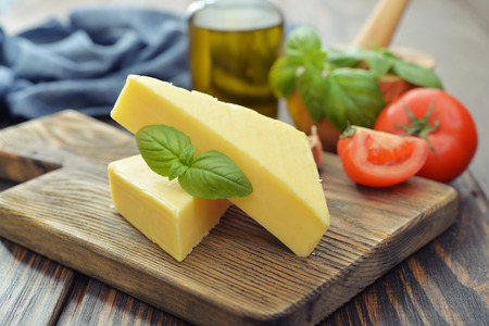 Hard cheese with basil on wooden cutting boardの写真素材
