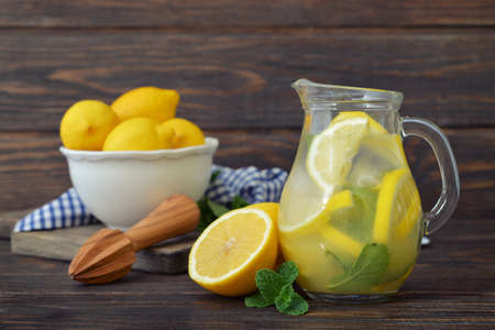 Lemonade with fresh lemon and mint in glass jug on wooden backgroundの写真素材