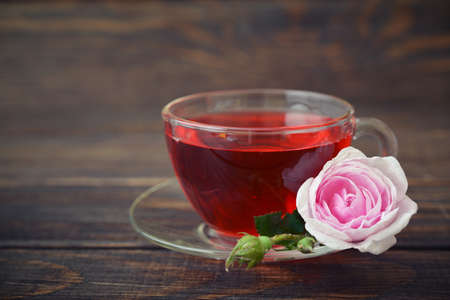Tea rose flowers and cup of tea on wooden backgroundの写真素材