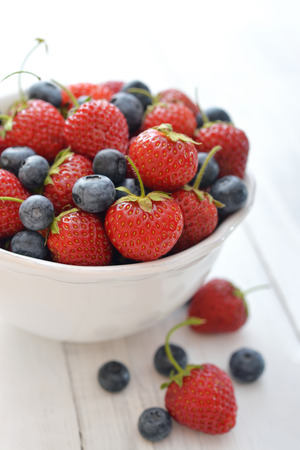 Fresh strawberry and blueberry in bowl on light の写真素材
