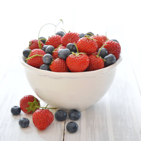 Fresh strawberry and blueberry in bowl on light の写真素材