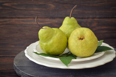 Fresh pears on plate over wooden background closeupの写真素材
