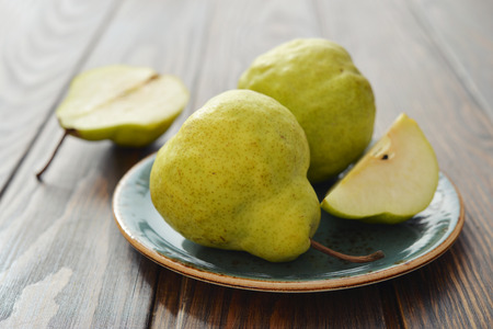 Fresh pears on plate over wooden background closeupの写真素材