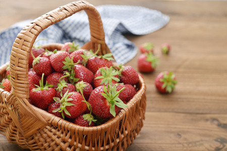 Fresh ripe strawberry in wicker basket on wooden backgroundの写真素材