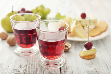 Glass of wine, camembert cheese and fresh fruits on wooden backgroundの写真素材