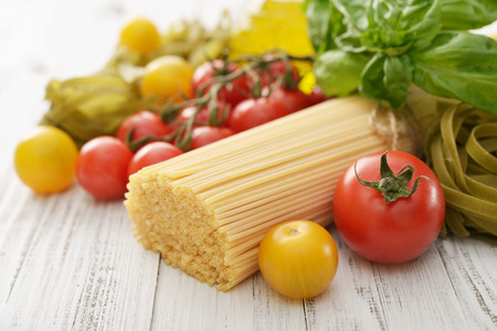 Spaghetti with fresh ripe tomato and basil on wooden background closeupの写真素材