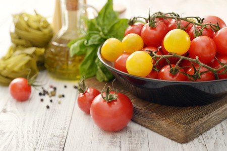 Fresh ripe tomato on plate, olive oil and basil on wooden background の写真素材