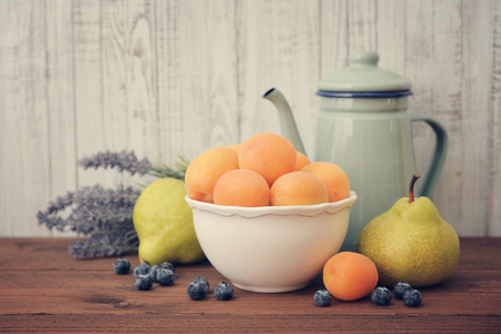 Apricots in bowl with fresh pear and blueberry on wooden backgroundの写真素材