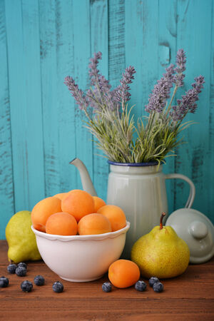Apricots in bowl with fresh pear and blueberry on wooden backgroundの写真素材