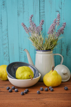 Pear in bowl with fresh blueberry and lavender flowers on wooden backgroundの写真素材