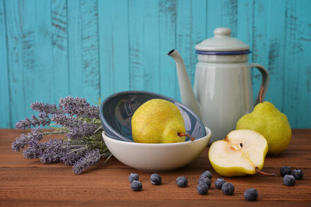 Pear in bowl with fresh blueberry and lavender flowers on wooden backgroundの写真素材