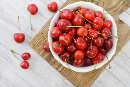 Fresh sweet cherries in bowl on wooden backgroundの写真素材