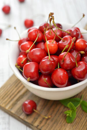 Fresh sweet cherries in bowl on wooden backgroundの写真素材