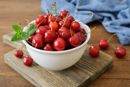 Fresh sweet cherries in bowl on wooden backgroundの写真素材
