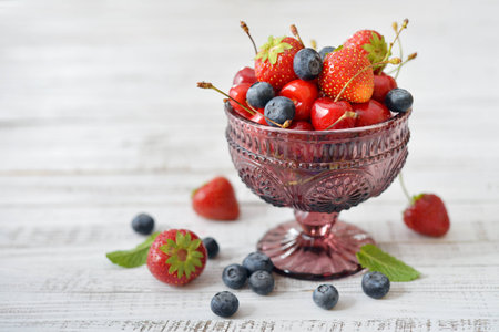 Fresh  ripe berries in glass vase n light backgroundの写真素材