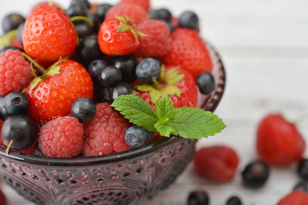 Fresh ripe berries in glass vase on light backgroundの写真素材