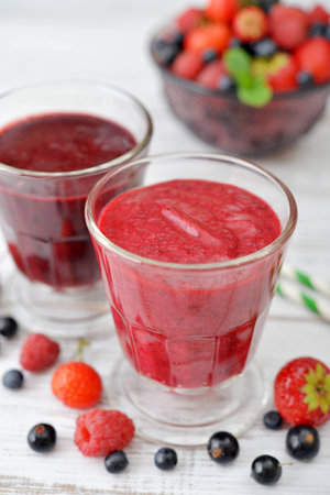 Fresh smoothies with ripe berries in glass vase  on light backgroundの写真素材