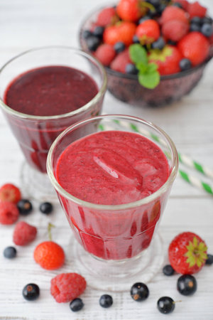 Fresh smoothies with ripe berries in glass vase  on light backgroundの写真素材