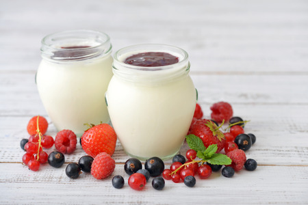 Yogurt with ripe fresh berry in jars on wooden backgroundの写真素材
