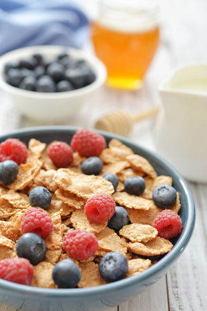 Whole-grain flakes in bowl with fresh berries on light backgroundの写真素材