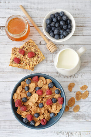 Whole-grain flakes in bowl with fresh berries on light backgroundの写真素材