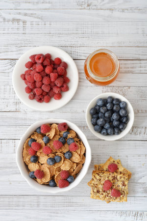 Whole-grain flakes in bowl with fresh berries on light backgroundの写真素材