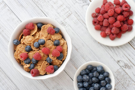 Whole-grain flakes in bowl with fresh berries on light backgroundの写真素材