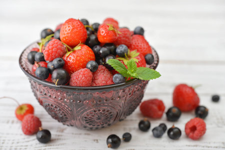 Fresh ripe berries in glass vase on light backgroundの写真素材