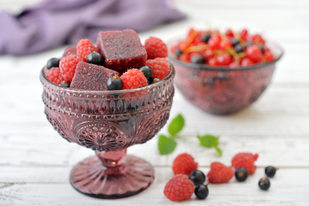 Jelly candy with fresh berries in glass vase on wooden backgroundの写真素材