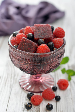 Jelly candy with fresh berries in glass vase on wooden backgroundの写真素材