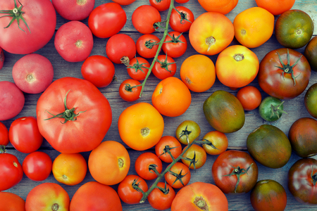 Different varieties of tomatoes on wooden background. Top view.の写真素材
