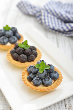Delicious mini tart with fresh blackberries and blueberries on wooden backgroundの写真素材