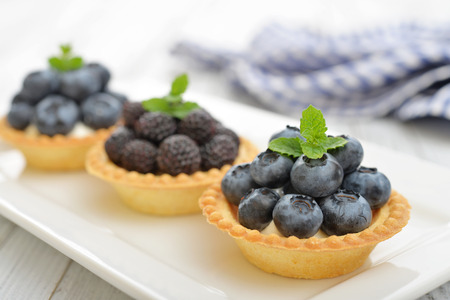 Delicious mini tart with fresh blackberries and blueberries on wooden backgroundの写真素材