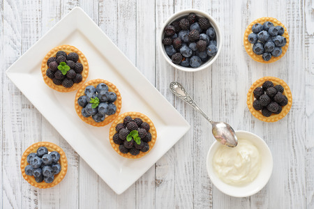 Delicious mini tart with fresh blackberries and blueberries on wooden backgroundの写真素材