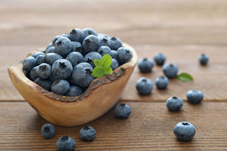 Fresh blueberry in wooden bowl on wooden backgroundの写真素材