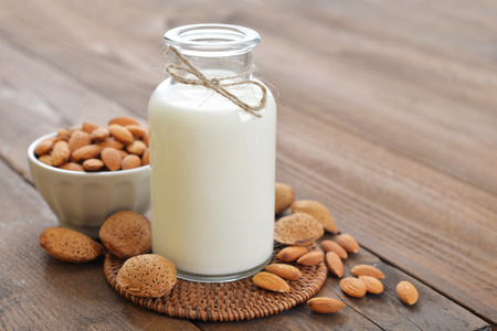 Almond milk in bottle with nuts on wooden backgroundの写真素材