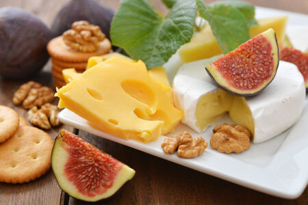 Different kinds of cheese with walnuts and fresh figs on wooden backgroundの写真素材