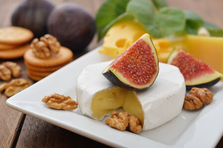 Camembert cheese with walnuts and fresh figs on wooden backgroundの写真素材