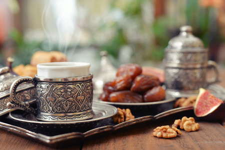 Cup of coffee with dry dates on metal oriental trayの写真素材