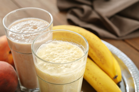 Banana smoothie in glass with fresh fruits and chocolate on wooden backgroundの写真素材