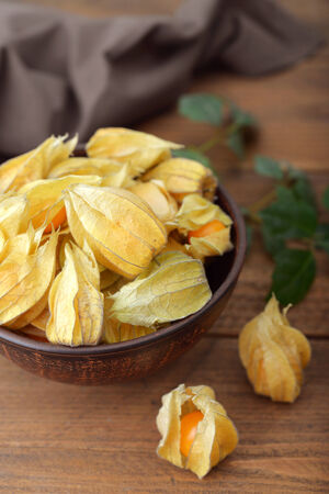 Physalis fruits in bowl closeup on wooden backgroundの写真素材