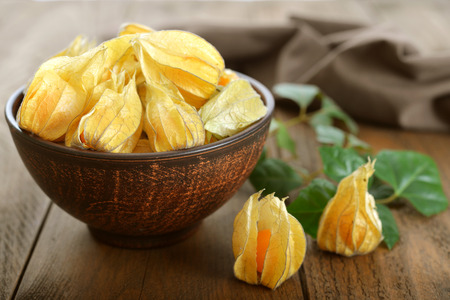 Physalis fruits in bowl closeup on wooden backgroundの写真素材