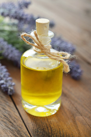 Essential lavender oil with fresh flowers on wooden background closeupの写真素材