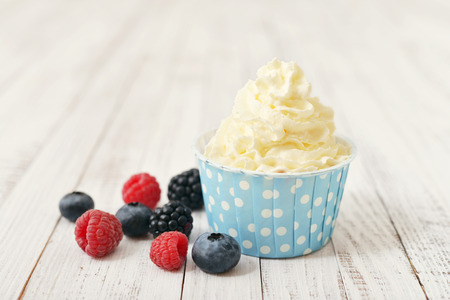 Fresh berries with frozen yogurt in paper cup on wooden backgroundの写真素材