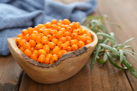 Sea-buckthorn berries in bowl on a wooden backgroundの写真素材