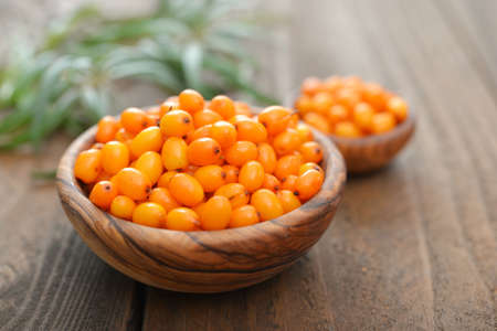 Sea-buckthorn berries in bowl on a wooden backgroundの写真素材